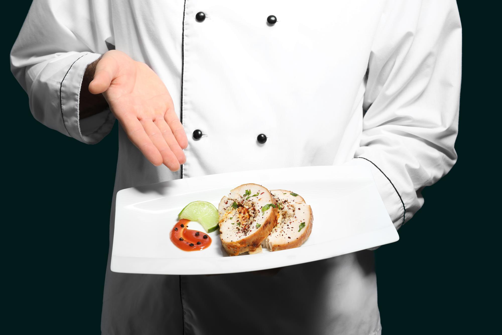 Chef arranging plated dessert on dark slate